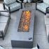 HPC Fire standard H-Burner lifestyle in a rectangular fire pit outdoors on a stone patio near patio furniture